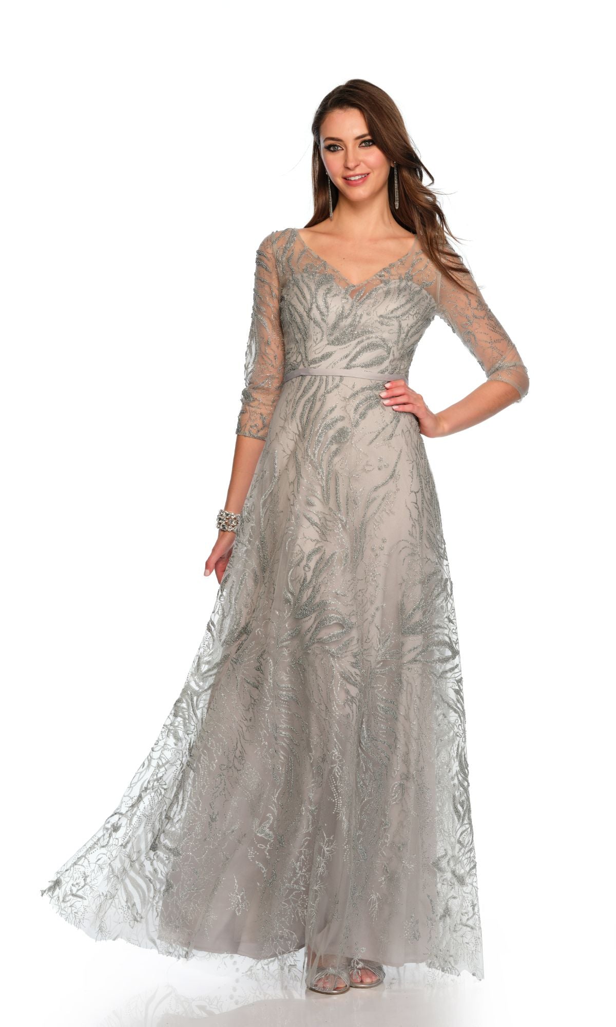 A woman poses in the Long Formal Dress 11606 by Dave and Johnny, a silver A-line gown with sheer three-quarter sleeves, intricate embroidery, and a subtle sweetheart neckline, set against a plain white background.